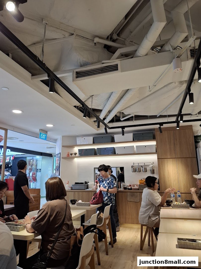 Diners are seated at tables inside a modern restaurant with exposed ceiling pipes and track lighting.