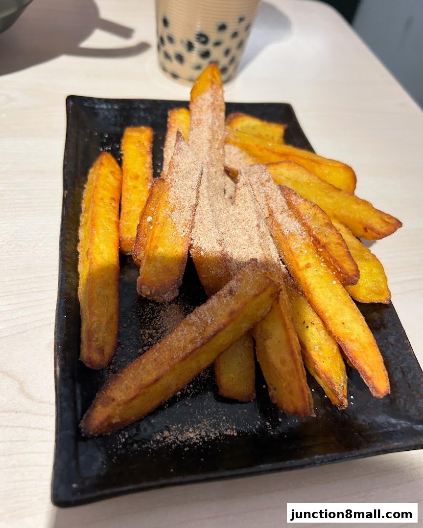 A plate of golden-brown sweet potato fries dusted with cinnamon sugar, served with a bubble tea.