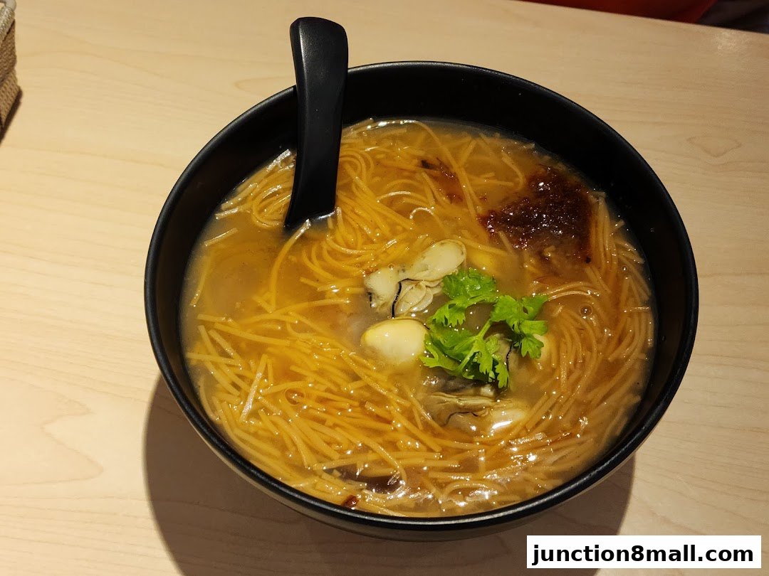 A close-up shot of a bowl of Taiwanese oyster vermicelli soup with a spoon.