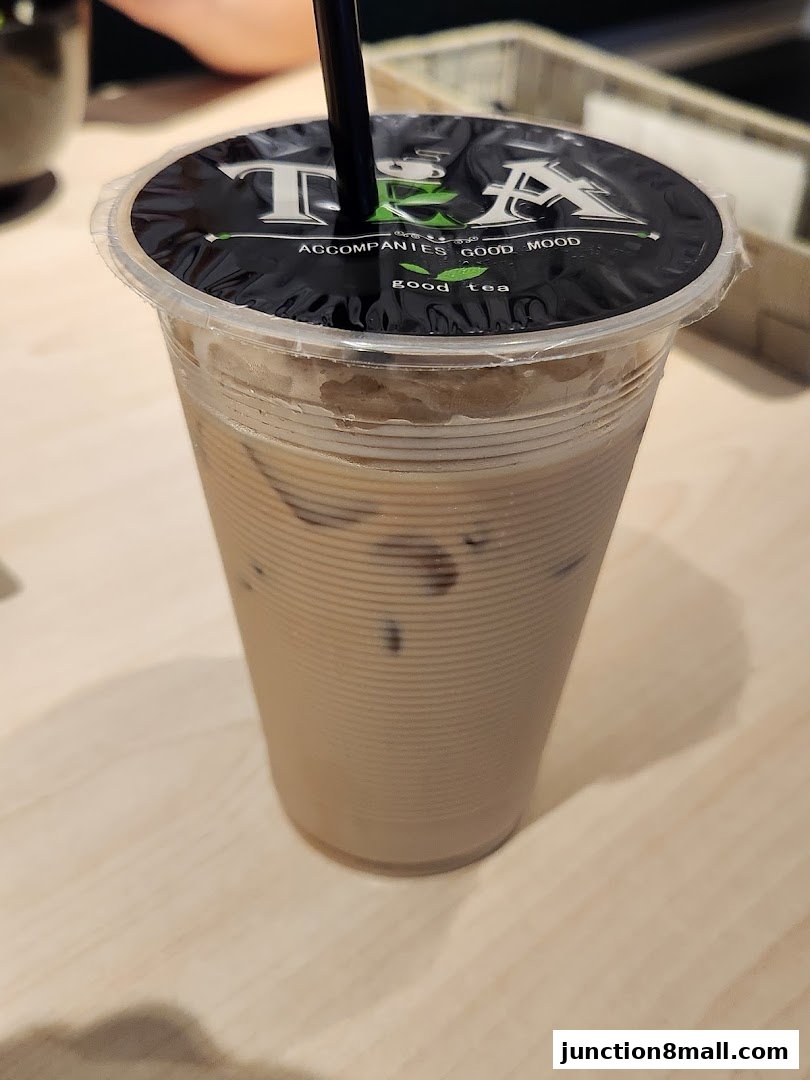 A close-up of an iced milk tea with the shop's logo on the lid.