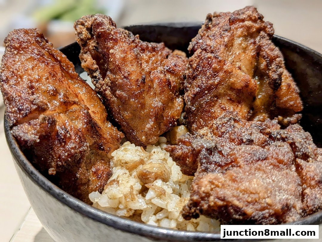 A close-up shot of crispy fried chicken pieces served over fluffy white rice in a bowl.