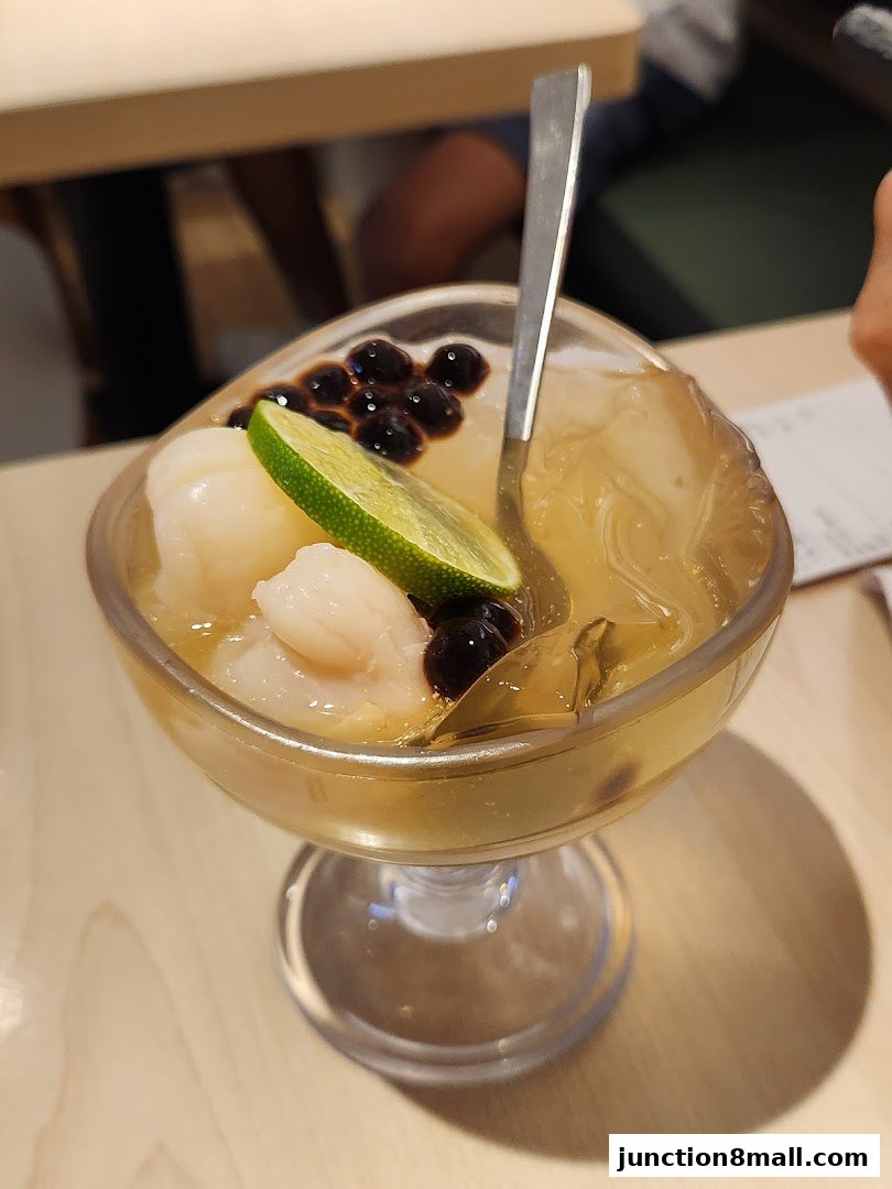 A refreshing Taiwanese dessert with lychee, boba pearls, and lime in a glass bowl.