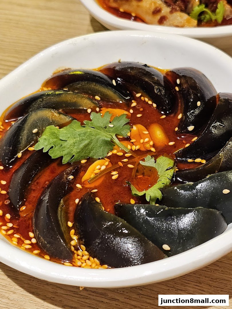 A close-up of preserved eggs in a spicy sauce with sesame seeds and cilantro.