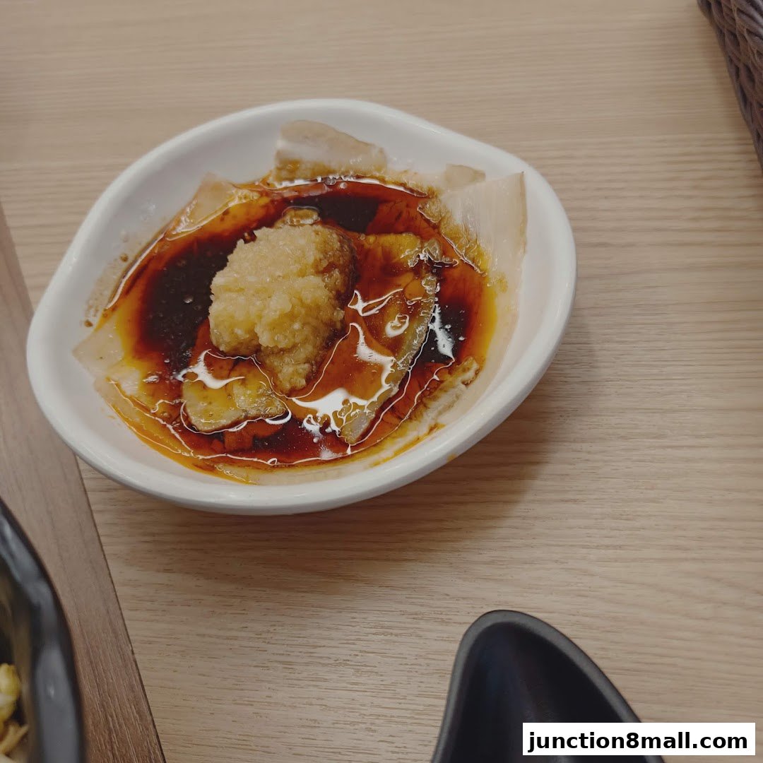 A close-up of a white bowl filled with a savory dish, featuring minced garlic and a rich sauce.