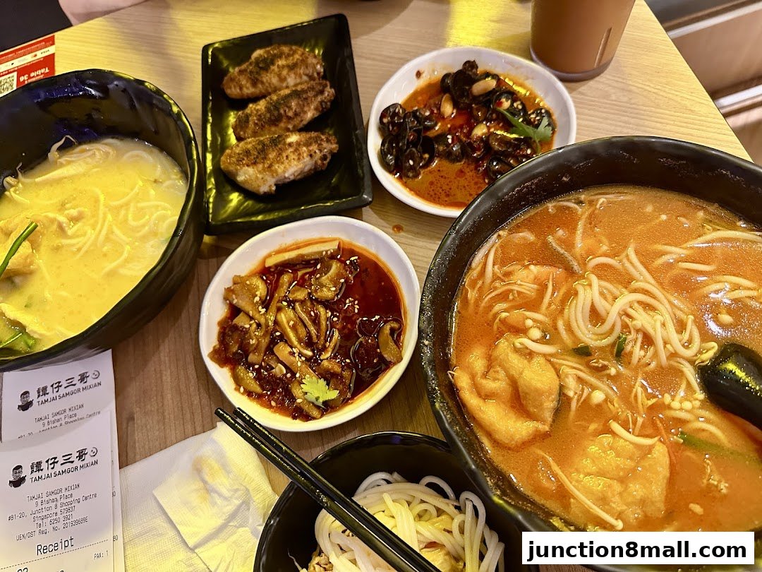 A table laden with delicious bowls of noodles, side dishes, and chicken wings.