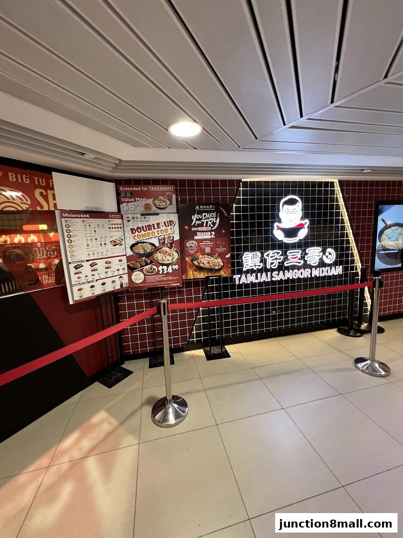 The entrance of TamJai SamGor Mixian, featuring menus and promotional posters with a distinctive logo.