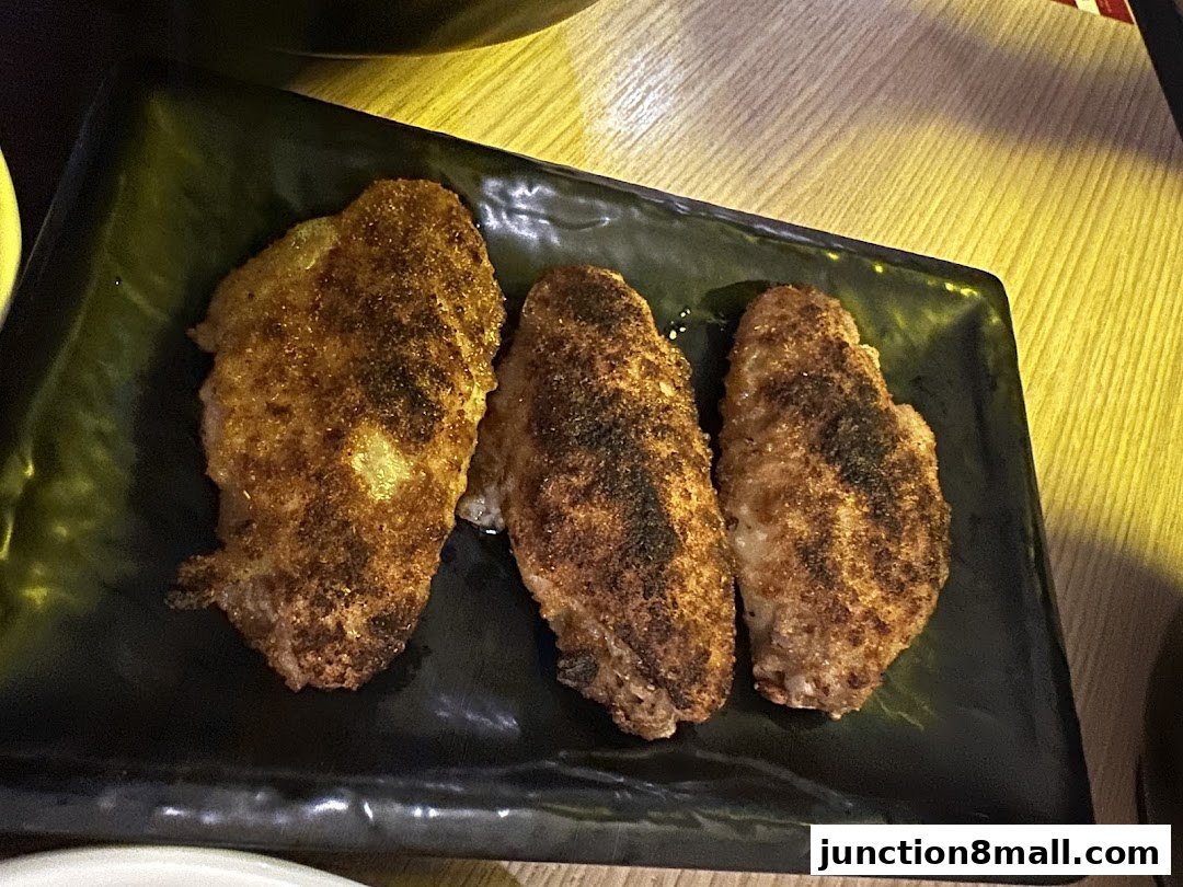 Three seasoned chicken wings served on a black rectangular plate.