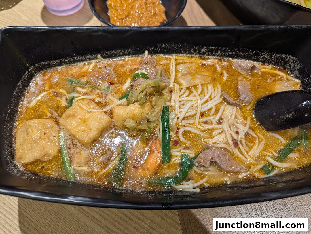 A close-up shot of a steaming bowl of noodle soup with various ingredients.