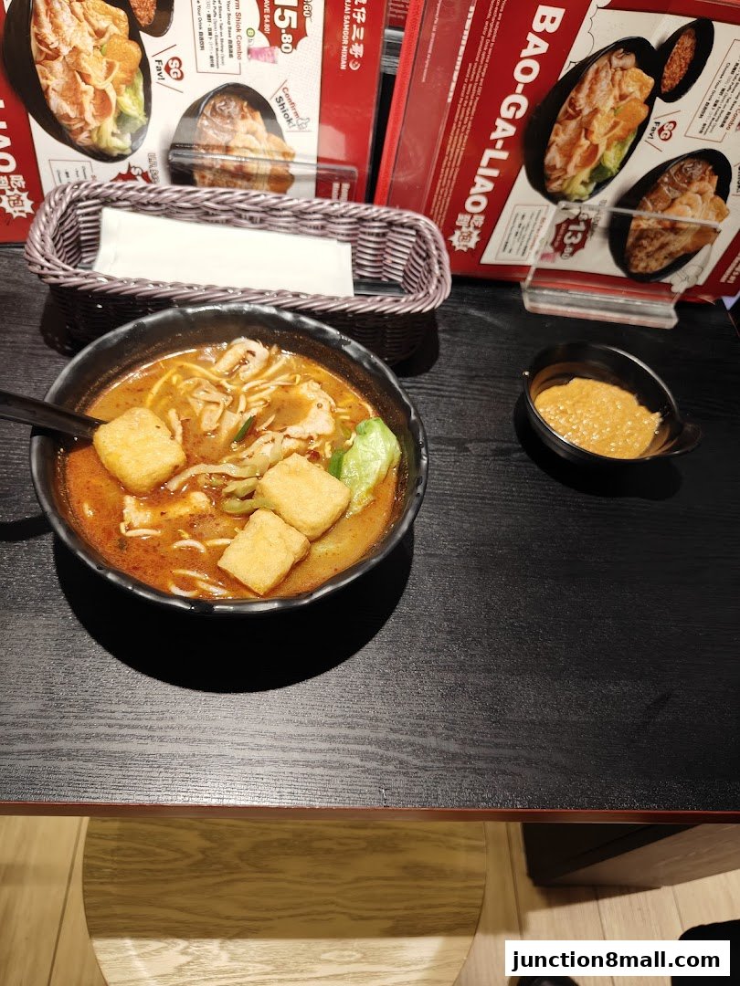 A close-up of a delicious bowl of noodles and a menu from TamJai SamGor Mixian.