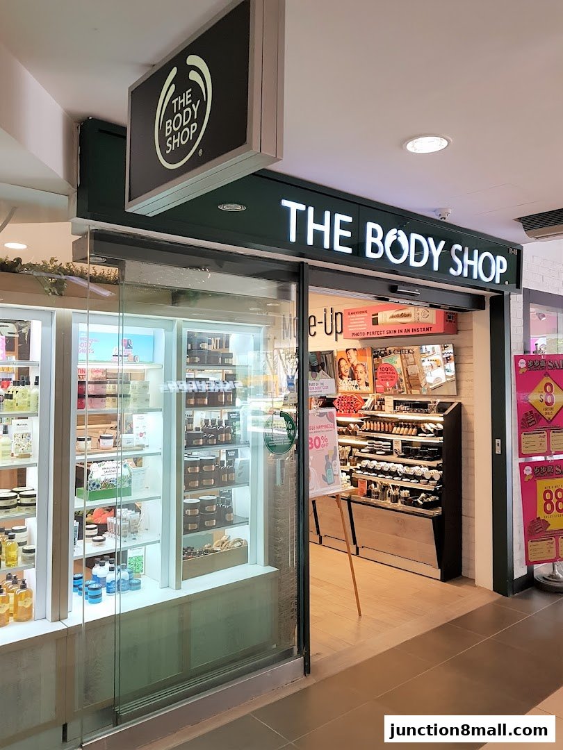 The Body Shop storefront with illuminated signage and displays of skincare and makeup products.
