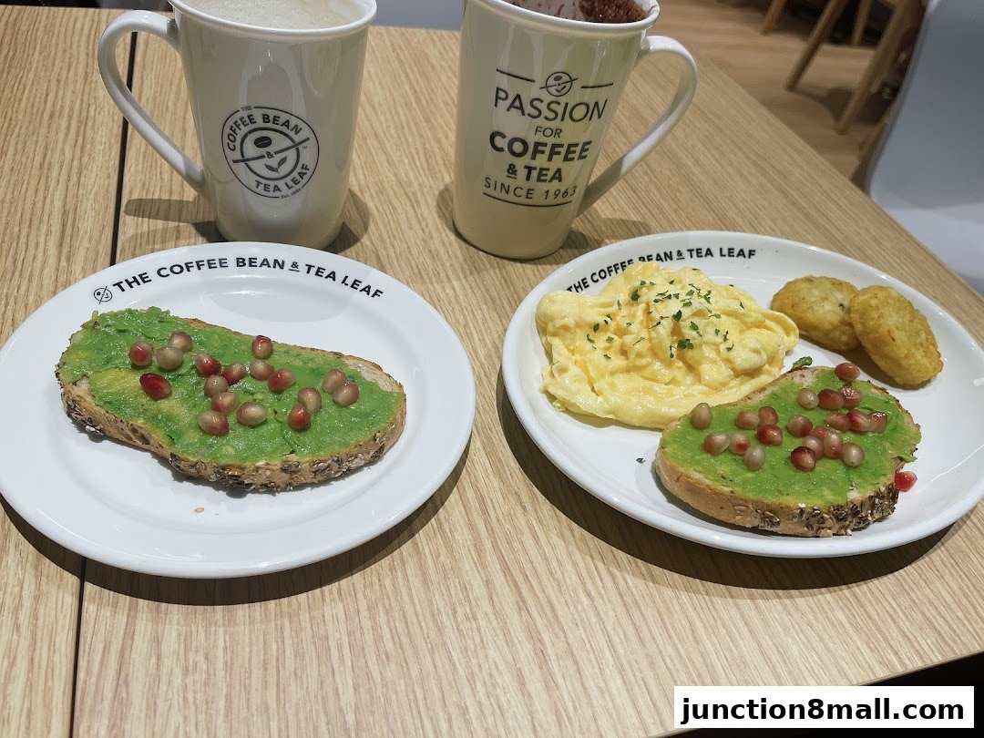 Two plates of avocado toast and scrambled eggs with hash browns, alongside coffee mugs.