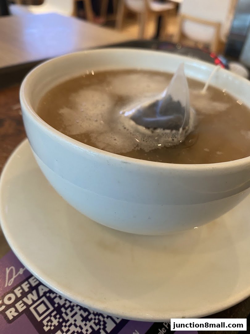 A close-up shot of a steaming cup of tea with a tea bag steeping in it.