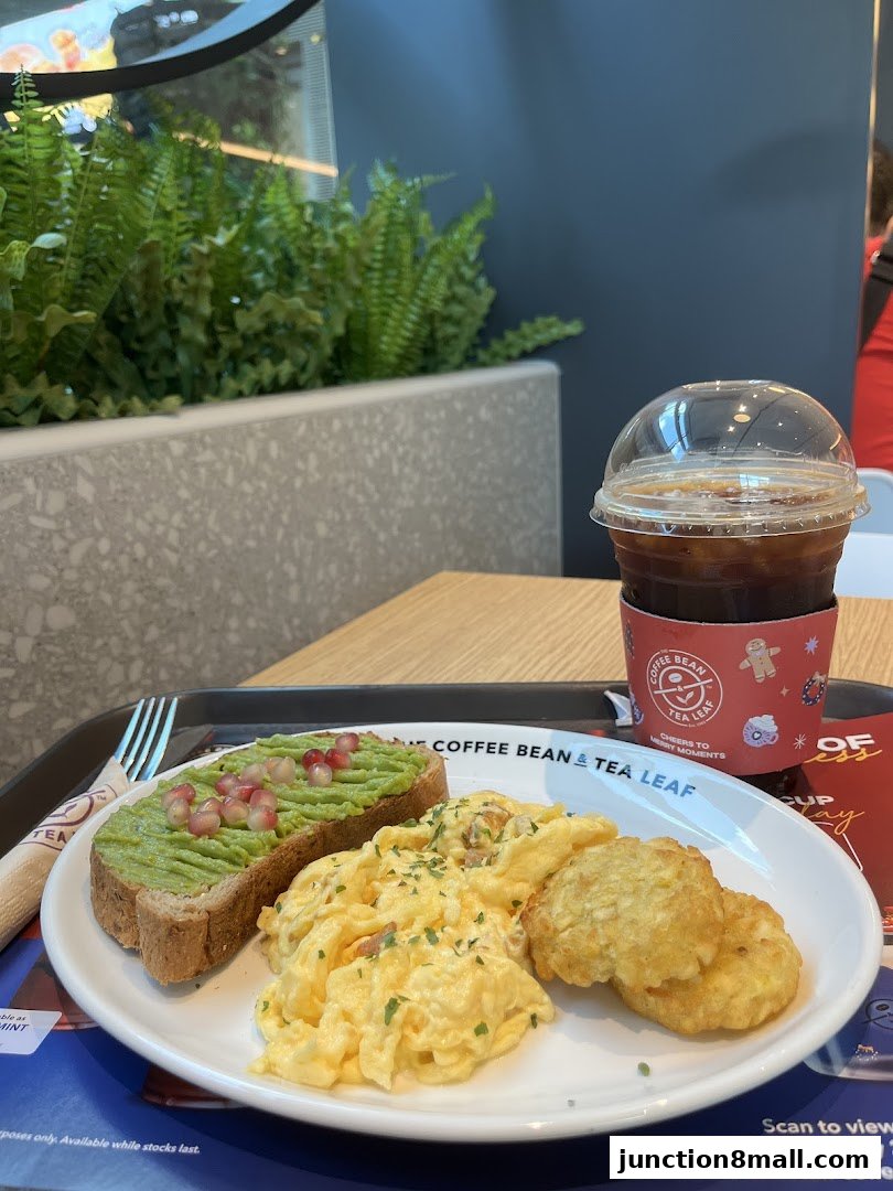 A breakfast spread with avocado toast, scrambled eggs, hash browns, and iced coffee.