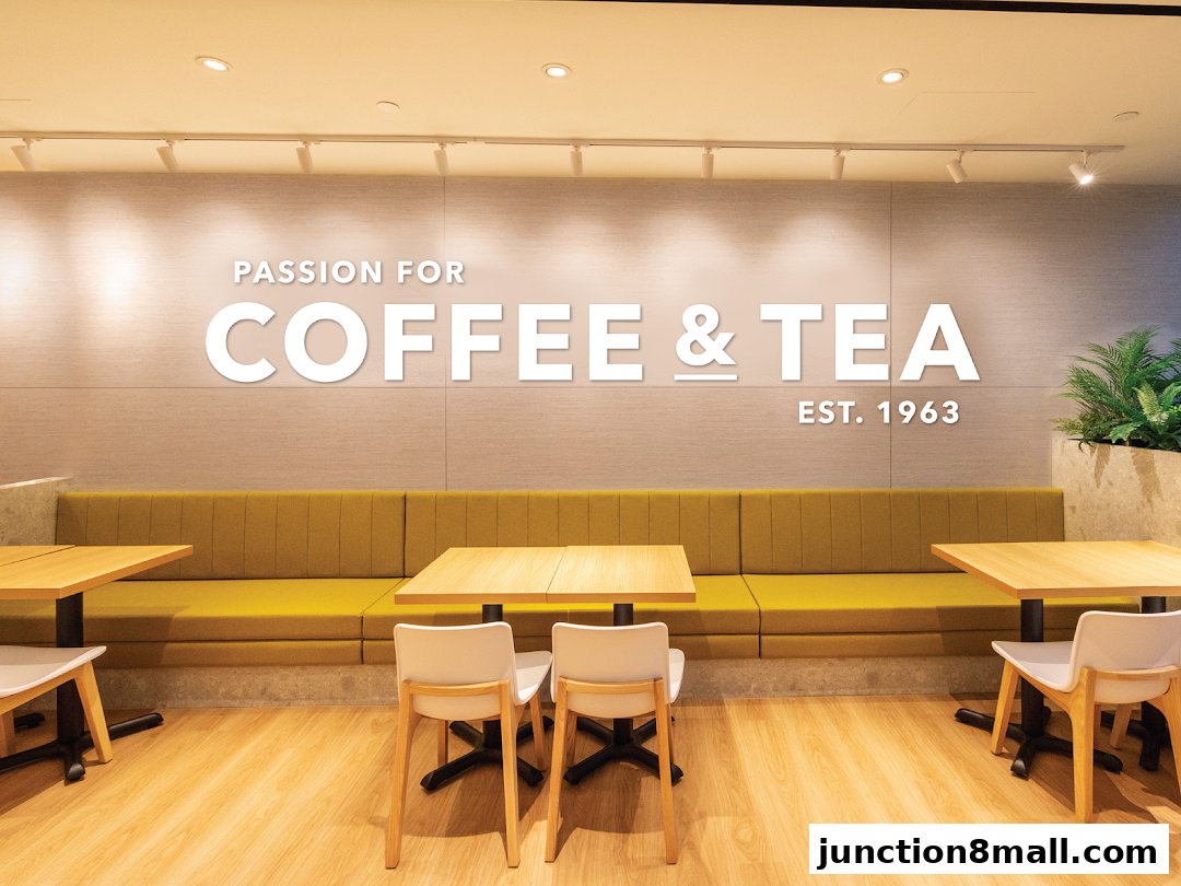 Interior of a coffee shop with seating, tables, and a wall graphic.