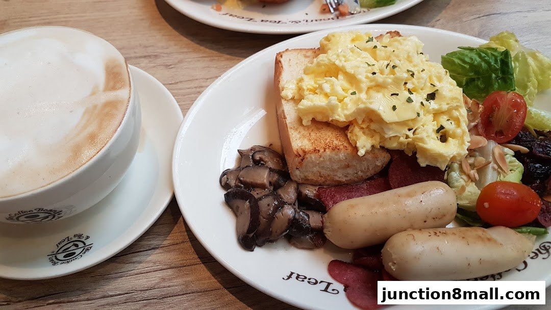 A delicious breakfast spread with scrambled eggs, sausages, mushrooms, and a latte.