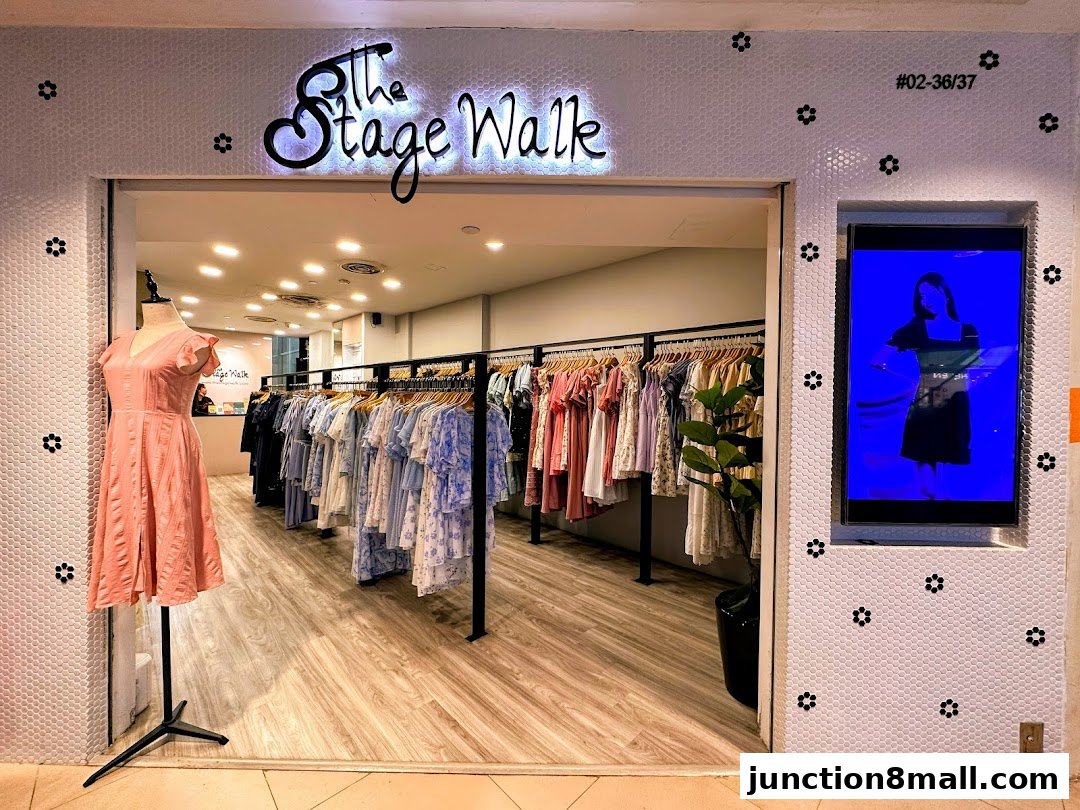 The entrance to 'The Stage Walk' boutique, showcasing dresses on a mannequin and racks of clothing.