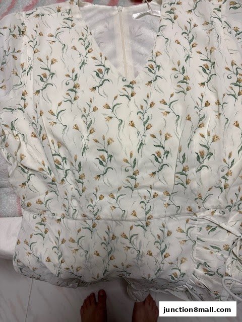 A close-up view of a white dress with a delicate floral print and a V-neckline.