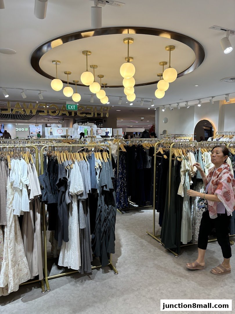 A woman browses through racks of stylish women's clothing in a well-lit boutique.