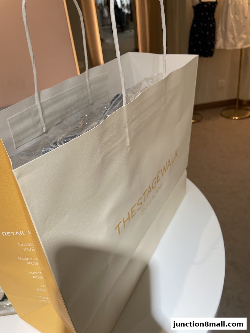 A white shopping bag with 'The Stage Walk' logo and shopping receipts.