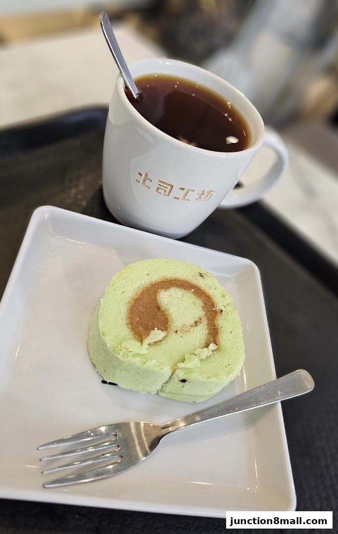 A slice of green swiss roll with caramel filling and a cup of coffee.