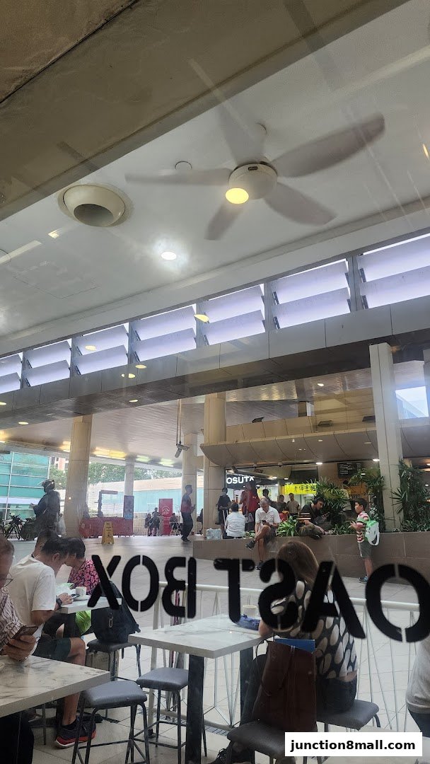 View through a window of people sitting at tables inside Toast Box Junction 8.