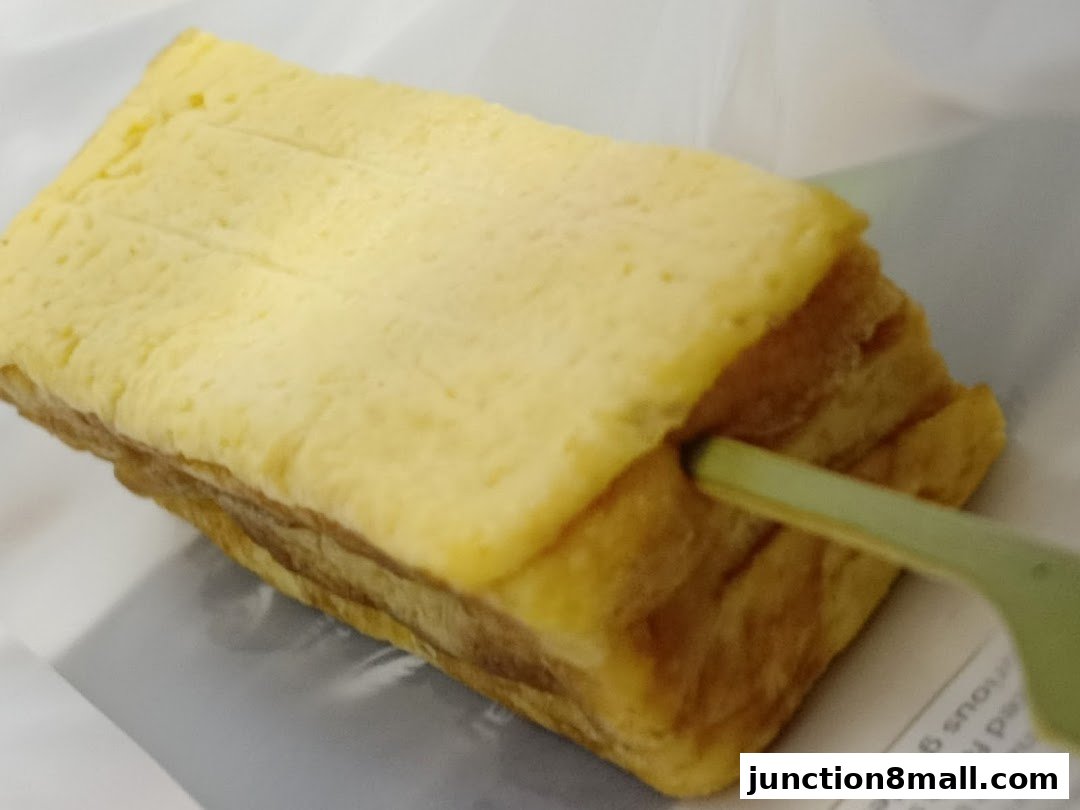 A close-up of a Japanese rolled omelet (tamagoyaki) on a stick, ready to eat.
