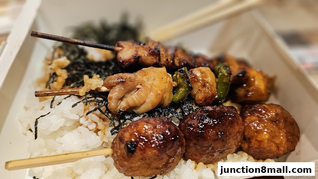 A close-up of a delicious bento box filled with rice, grilled chicken skewers, and meatballs.