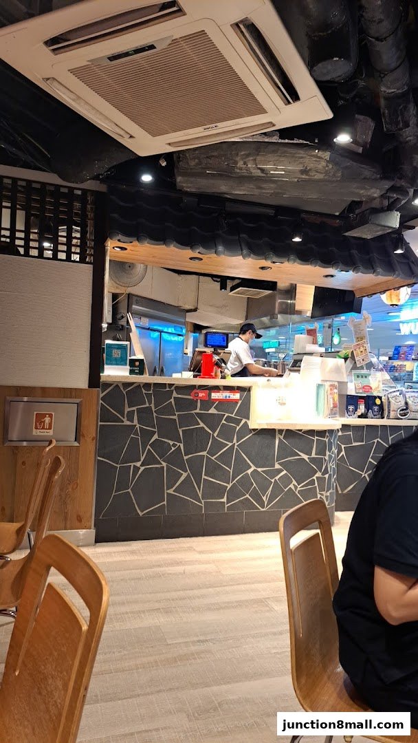 A view of the counter area and seating at Tori-Q Junction 8 with a staff member preparing food.