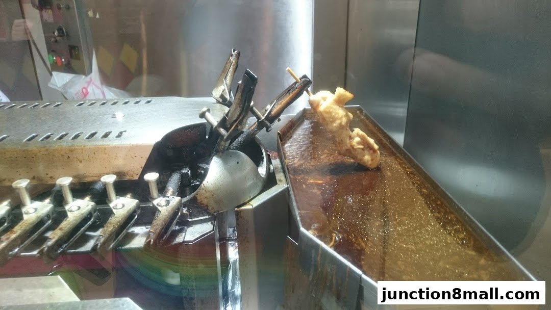 A close-up of a food preparation machine with skewers of fried food.
