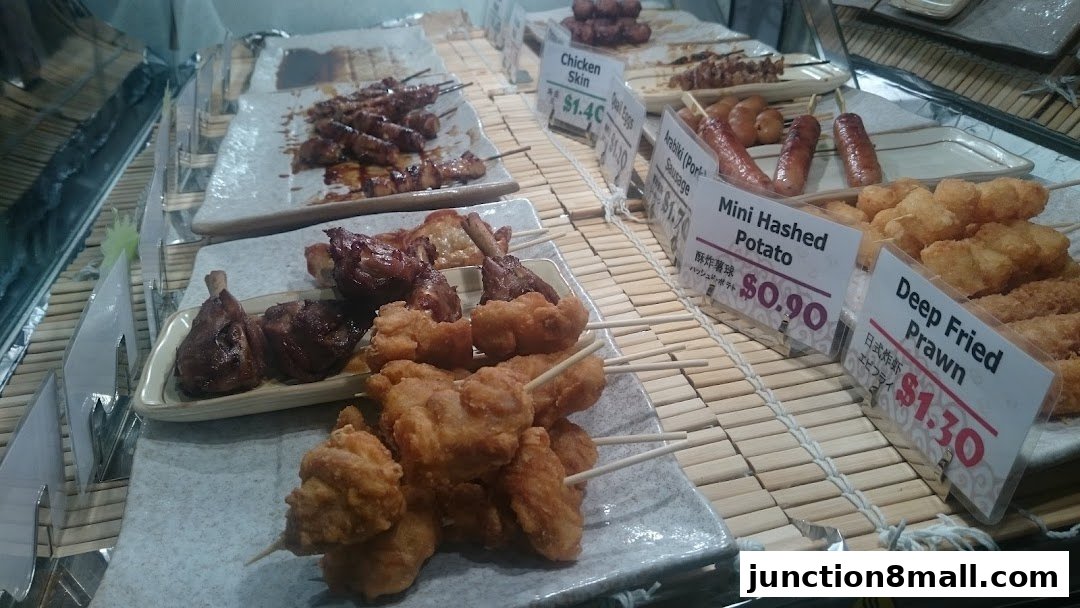 A display of various grilled and fried skewers, including chicken, sausages, and seafood.