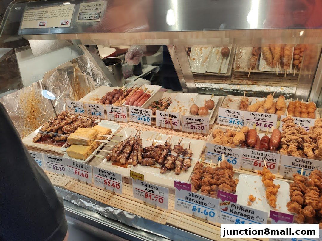 A display of various Japanese skewers and fried items with price labels.