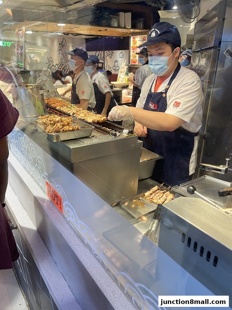 Staff preparing skewers at a Tori-Q restaurant counter.