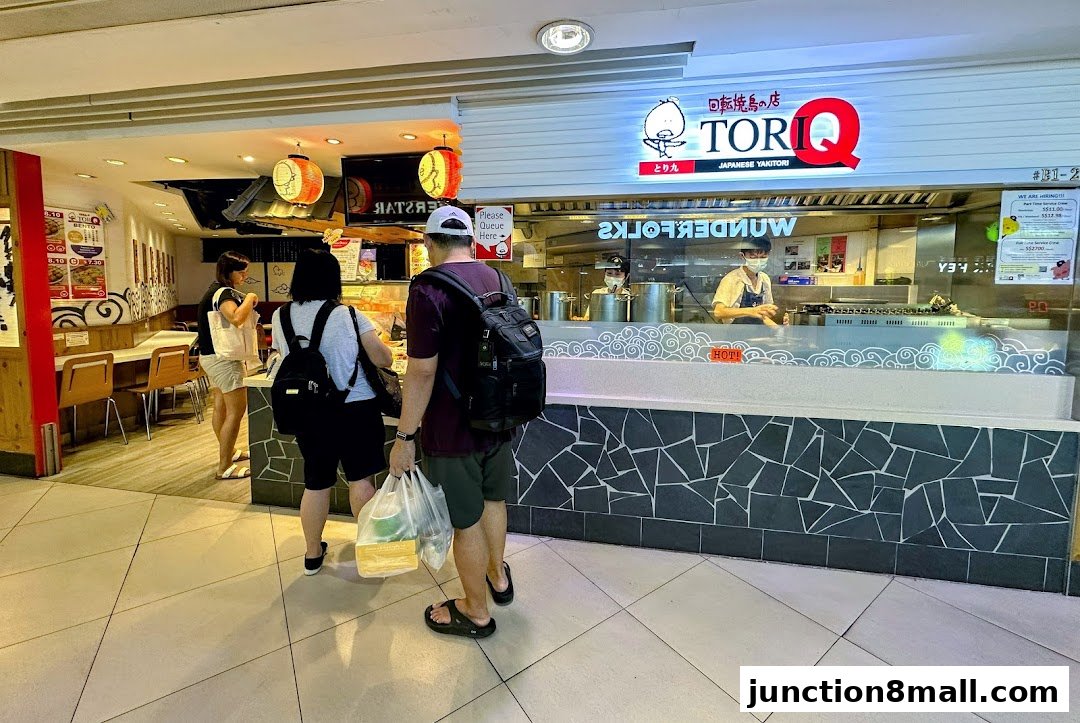 People queuing at Tori-Q, a Japanese Yakitori shop with staff preparing food behind the counter.