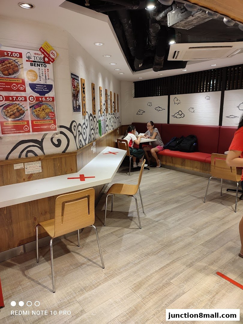 Interior of a Tori-Q restaurant with seating, a counter, and a menu board displaying bento boxes.