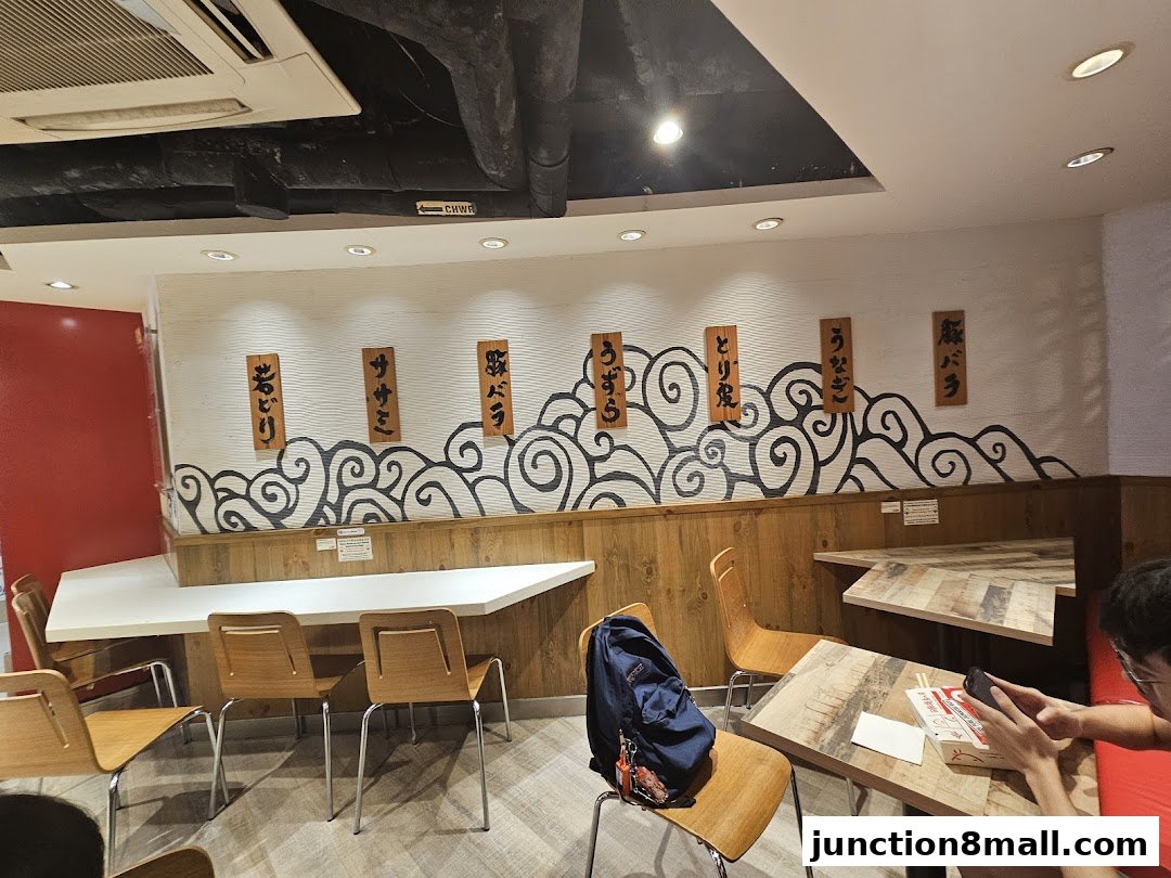 Interior of a Japanese restaurant with wooden tables, chairs, and decorative wave patterns on the wall.