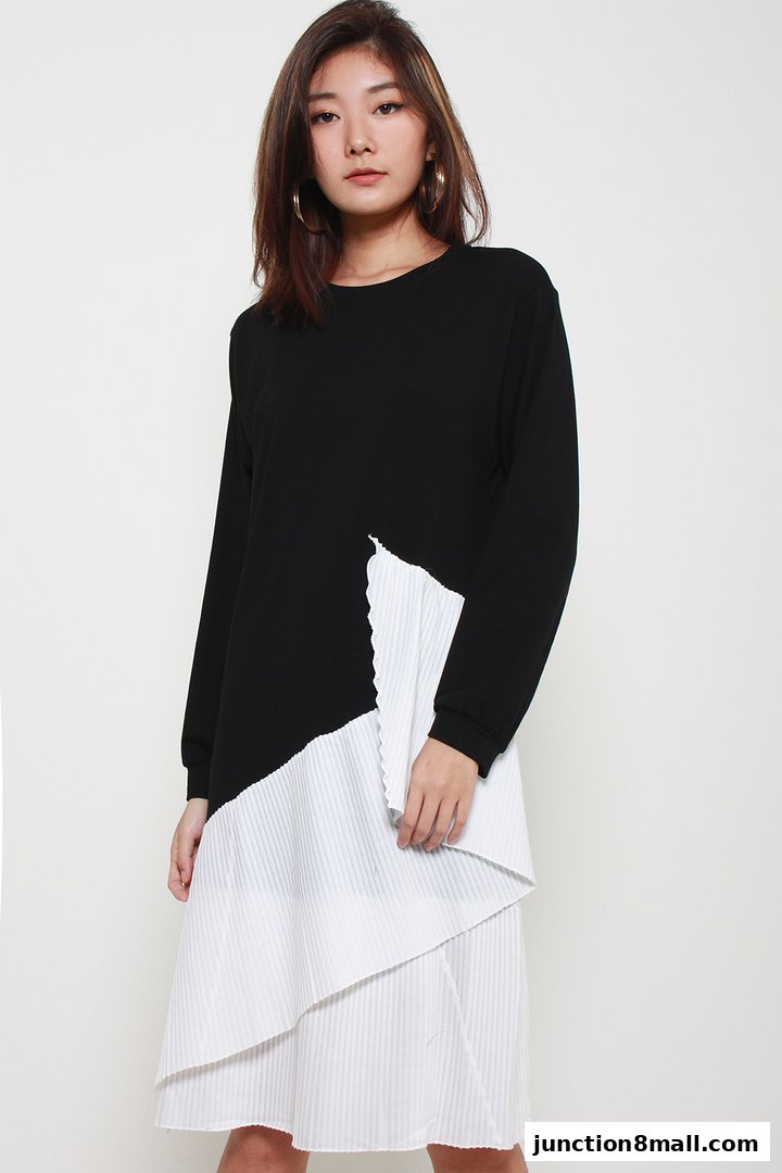 A young woman models a black long-sleeved top with a white pleated asymmetrical overlay.