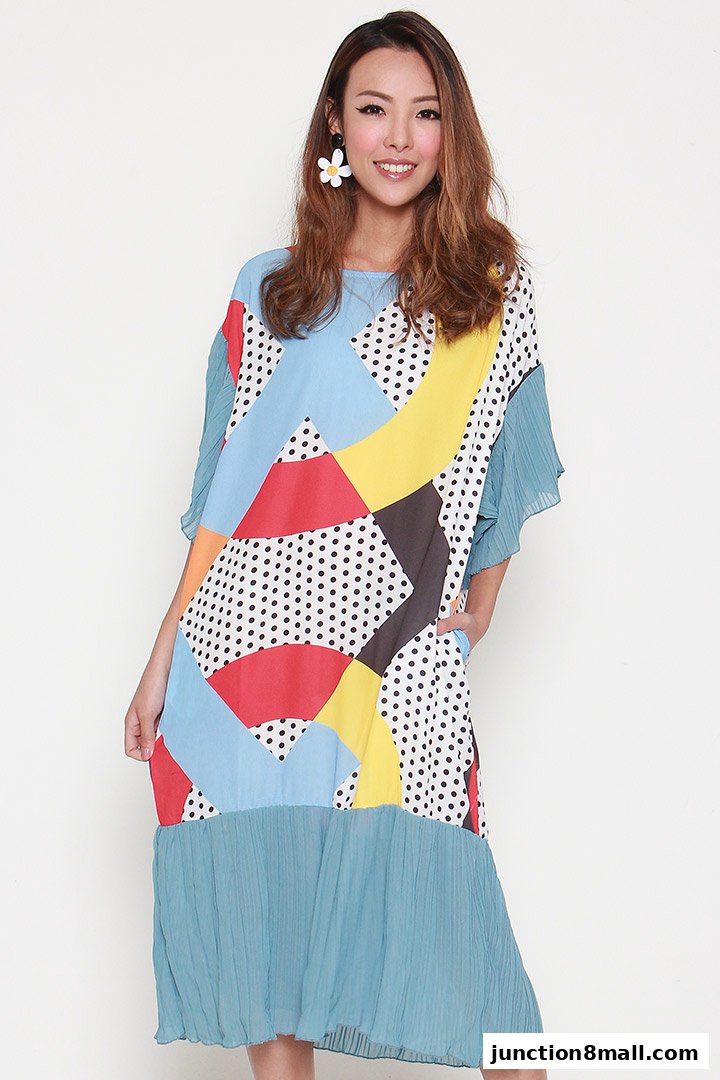 A woman models a colorful, abstract print dress with pleated sleeves and hem.