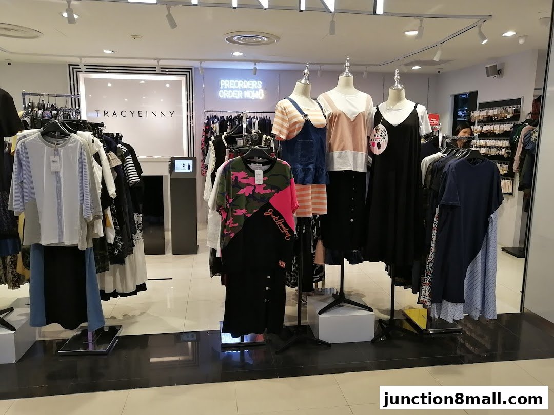 A well-lit clothing store interior with mannequins displaying outfits and racks of apparel.