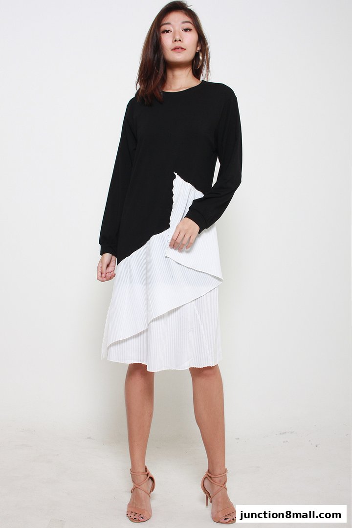 A woman models a black and white pleated dress with high heels.