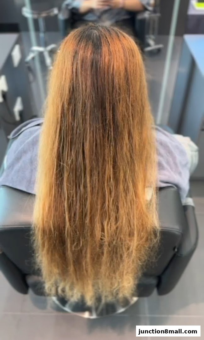 A person's long, blonde-brown hair is shown from behind, styled in a salon.