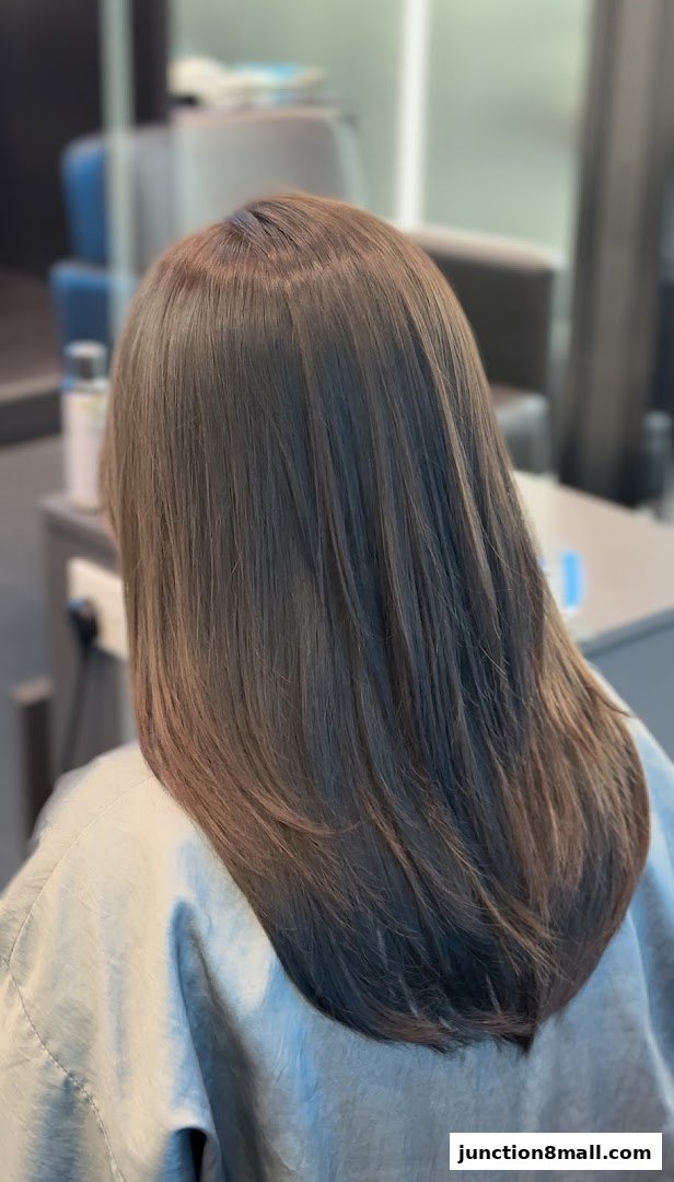 A person's back with freshly styled, layered brown hair in a salon setting.