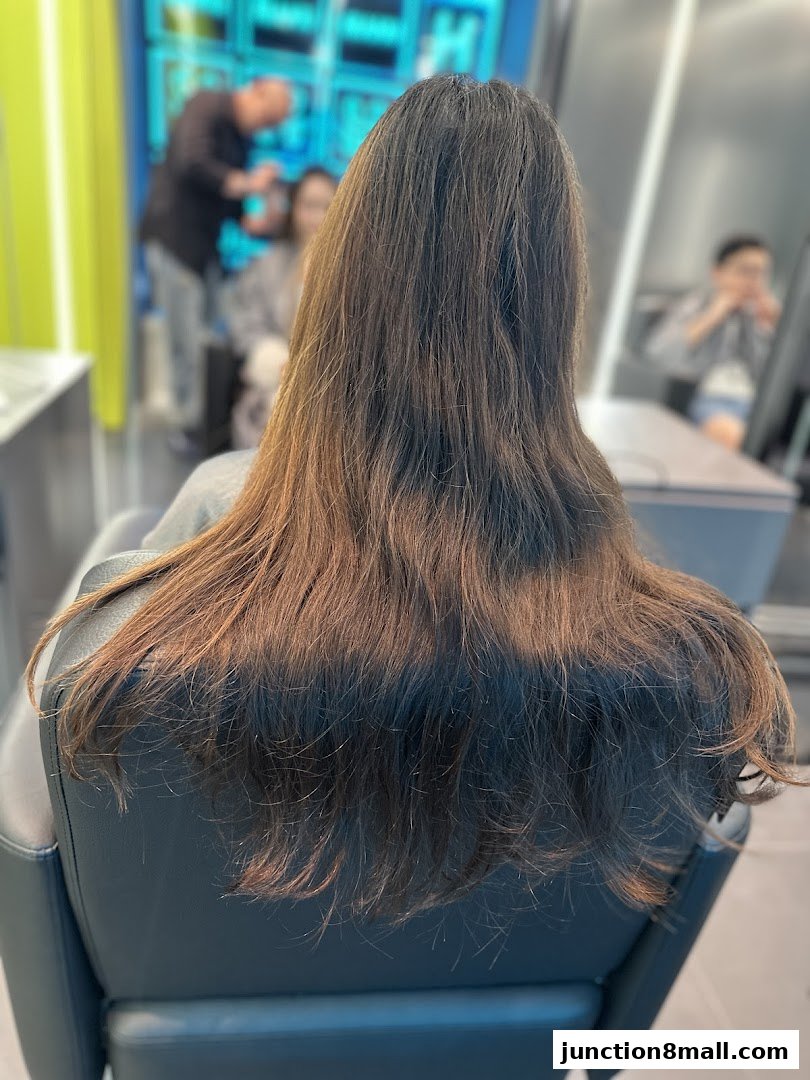 A person sits in a salon chair, their long brown hair styled and ready for a treatment.