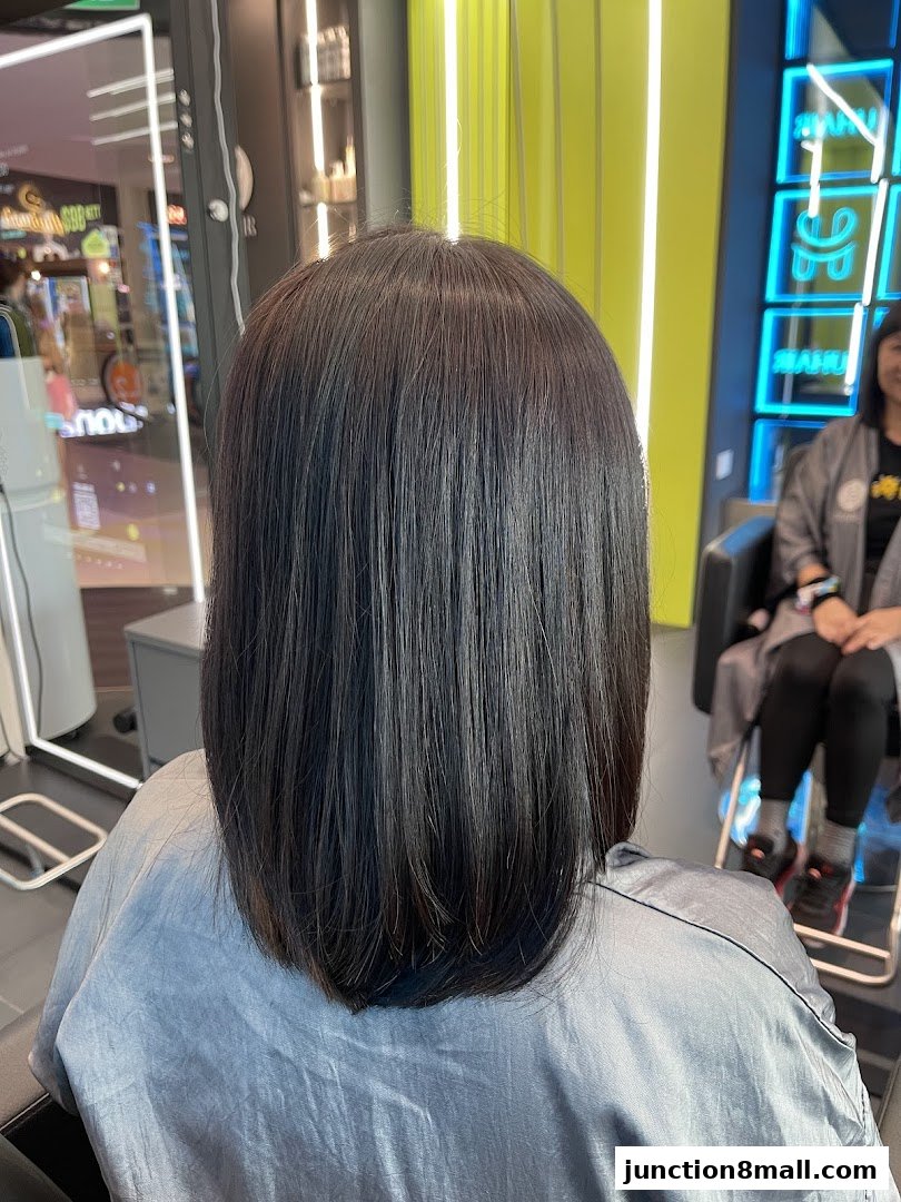 A person's back with freshly styled, dark, shoulder-length hair in a salon.