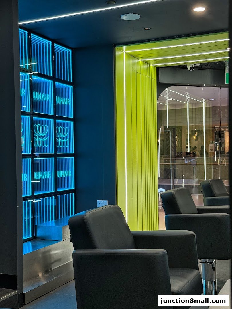 Interior of a modern hair salon with black chairs and neon blue and green lighting.