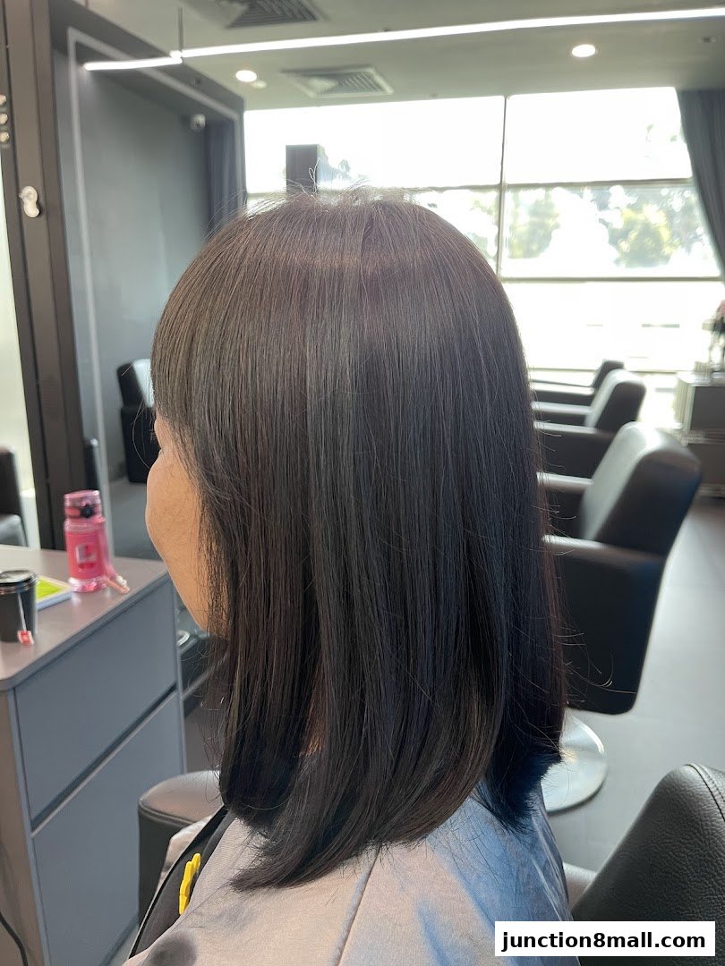 A woman with freshly styled dark hair sits in a salon chair, ready for a new look.