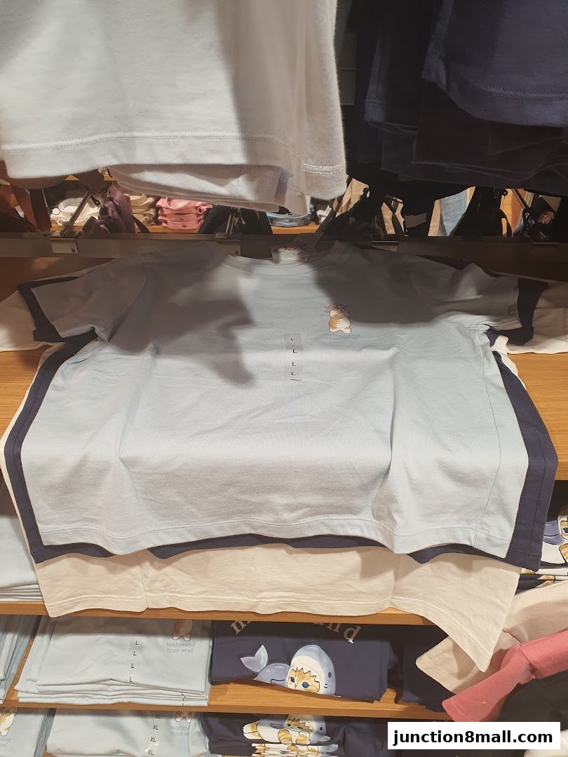 A display of folded t-shirts with cartoon graphics on shelves in a retail store.