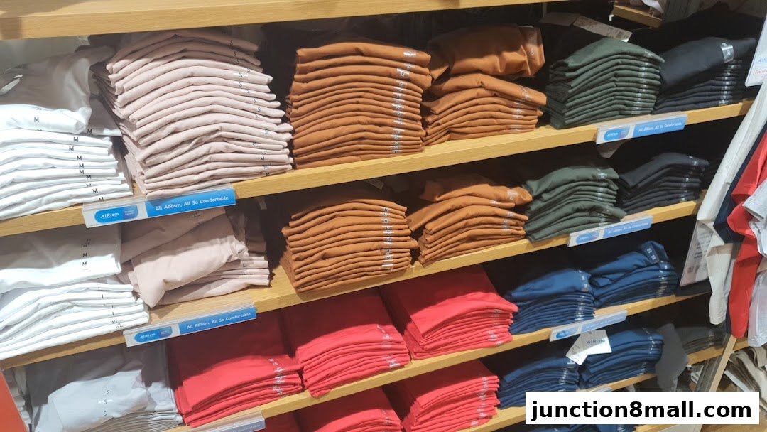 Neatly folded t-shirts in various colors displayed on store shelves.