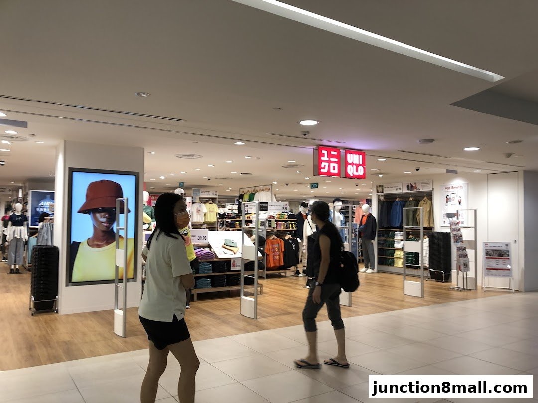 Interior view of a UNIQLO store with clothing displays and shoppers.