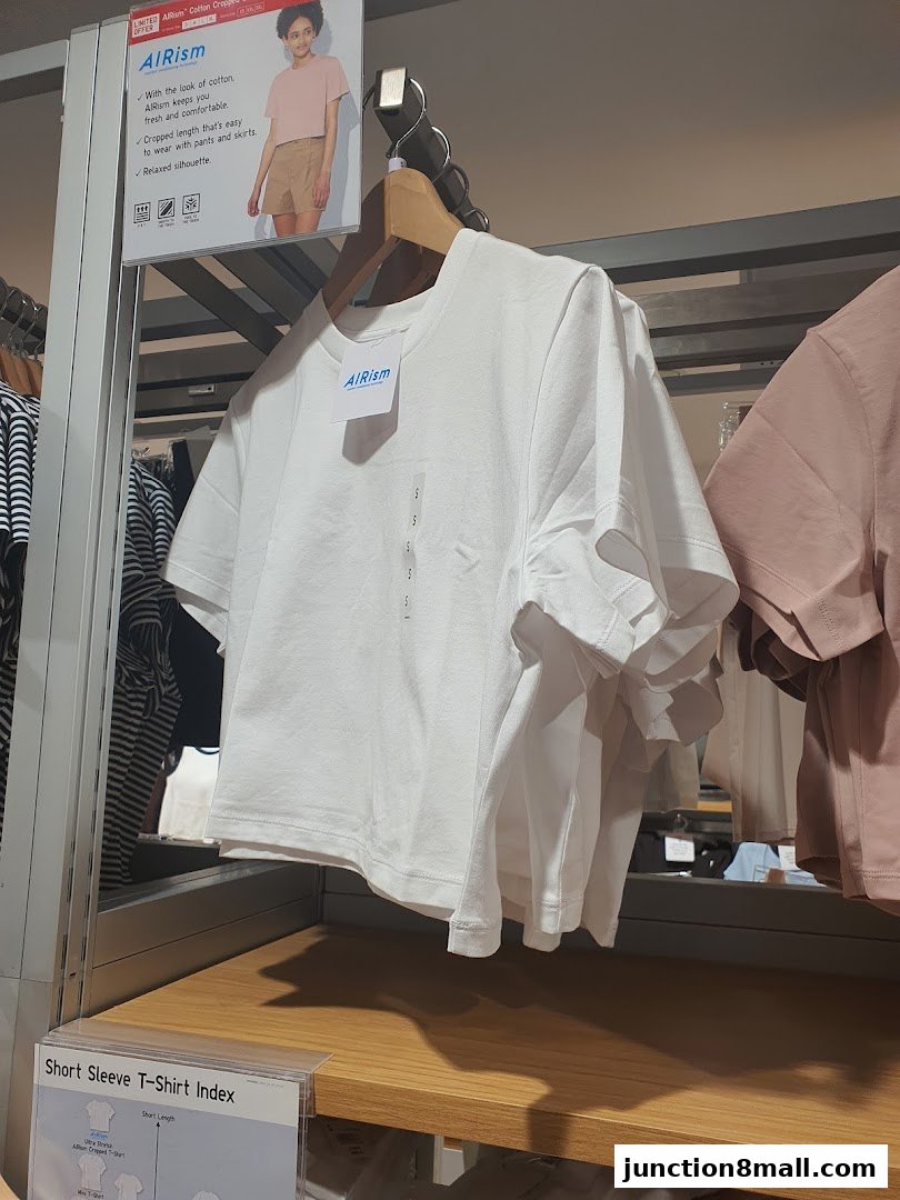 White AIRism cotton cropped t-shirts displayed on hangers with a product information sign.