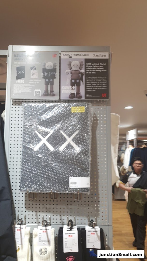 UNIQLO store display featuring KAWS + Warhol collaboration apparel and accessories.